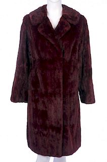 A knee-length dyed ermine coat. With a notched lapel collar, hook and eye fastenings, two outer pock