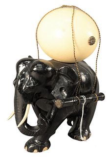 Wood Carved Elephant, in ebonized lacquer carrying ostrich egg, height 13 inches, length 10 inches.