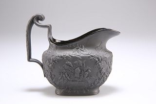 AN EARLY 19TH CENTURY BLACK BASALT CREAM JUG, moulded with 