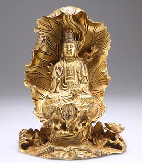 A CHINESE GILT-BRONZE BUDDHA, cast seated on a lotus leaf, 