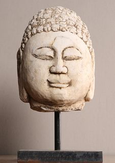 A CHINESE CARVED LIMESTONE HEAD OF BUDDHA, on a stand. 38cm