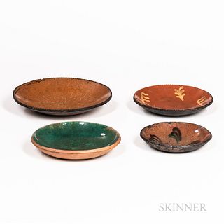 Four Glazed Redware Plates, 19th century, the smallest with brown and green "feather" slip, one with green glaze, one with yellow slip,