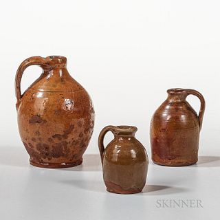 Three Small or Miniature Glazed Redware Jugs, New England, 19th century, a Massachusetts orange-glazed ovoid jug with molded handle, a
