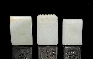 Three Chinese pale celadon jade plaques, one depicting fruit and a bat with a figure verso, 5cm high
