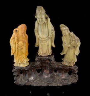Set of three Chinese carved soapstone figures of immortals on naturalistic base, overall 22.5cm high