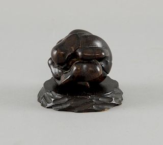Japanese carved hardwood figure of a man sitting cross-legged and bent over double with his head in
