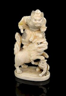 Japanese carved ivory figural group of a bearded man standing on the back of a lion with it's front