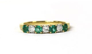 An 18ct gold emerald and diamond half eternity ring