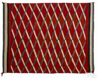 Navajo weaving with repeating diamonds on a red field with a triple border, 64'' x 50''.