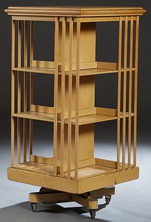 English Style Carved Blonde Mahogany Revolving Bookmill, early 20th c., the stepped square top over slatted shelves on all sides, to a square plinth, 