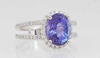 Lady's Platinum Dinner Ring, with an oval 3.78 carat tanzanite atop a border of tiny round diamonds, the split shoulders of the band also mounted with