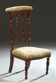 French Carved Mahogany Prie Dieu, 19th c., the padded armrest on a Gothic arch and trefoil spindled back, to a trapezoidal bowed seat, on turned taper