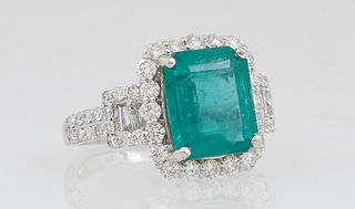 Lady's Platinum Dinner Ring, with a 4.05 carat emerald, atop a conforming border of round diamonds, the shoulders of the band with baguette mounted lu
