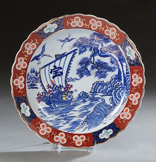 Oriental Porcelain Charger, 20th c., the scalloped gilt edge around a wide porcelain floral band, enclosing a reserve of a boat on water, storks, tree