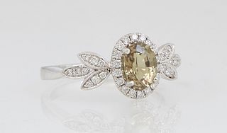 Lady's 18K White Gold Dinner Ring, with an oval 1.07 carat alexandrite atop a border of tiny round diamonds, flanked by diamond mounted leaf form lugs