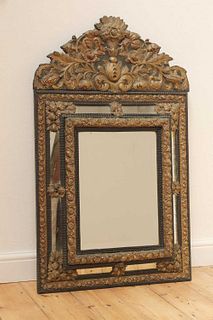 An ebonised and embossed brass wall mirror,