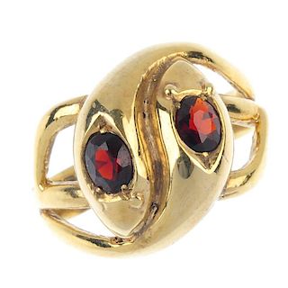 A 9ct gold garnet snake ring. Of openwork design, comprising two intertwined snakes, each with oval-