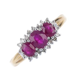A 9ct gold ruby three-stone and diamond cluster ring. The slightly graduated oval-shape ruby line, w