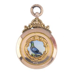 A 1920s 9ct gold enamel pigeon medallion. The enamel pigeon, within a circular-shape surround, to th