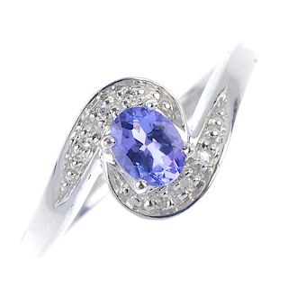 A 9ct gold tanzanite and diamond crossover ring. The oval-shape tanzanite, to the pave-set single-cu