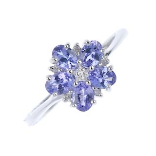 A 9ct gold tanzanite and diamond cluster ring. The single-cut diamond, within an oval-shape tanzanit