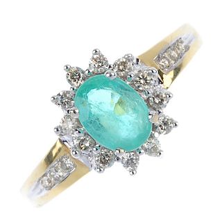 * An 18ct gold emerald and diamond cluster ring. The oval-shape emerald, within a brilliant-cut diam