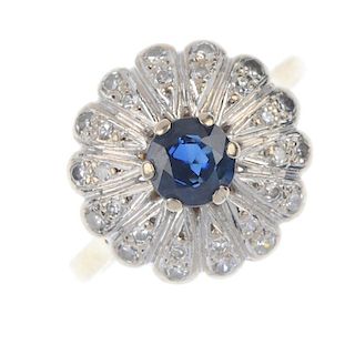 A 1960s 18ct gold sapphire and diamond cluster ring. The circular-shape sapphire, with graduated sin