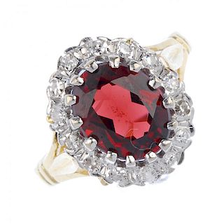 A 18ct gold garnet and diamond cluster ring. The oval-shape garnet, within a single-cut diamond surr
