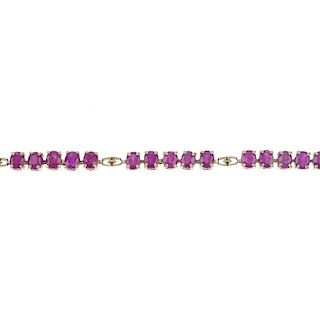 A 9ct gold ruby bracelet. Designed as a series of oval-shape ruby lines, with openwork spacers, to t