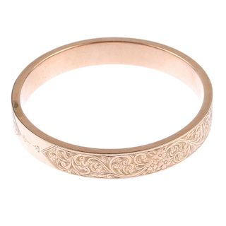 An early 20th century 9ct gold bangle. The wide bangle, with repeated scrolling floral engraved moti