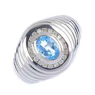 A topaz and diamond ring. The oval-shape topaz collet, within a brilliant-cut diamond border, to the