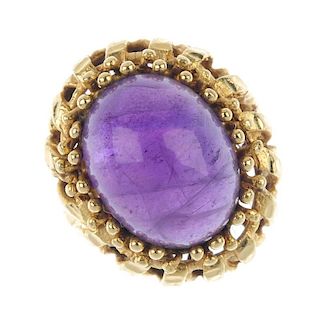 An amethyst single-stone ring. The oval amethyst cabochon, within a bead surround, to the openwork t