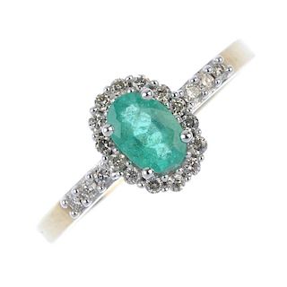 * A 9ct gold emerald and diamond cluster ring. The oval-shape emerald, within a brilliant-cut diamon