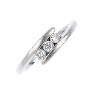 An 18ct gold diamond three-stone ring. The brilliant-cut diamond diagonal line, to the crossover sho