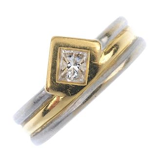 A diamond single-stone ring. The rectangular-shape diamond collet, off-set to the bi-colour grooved