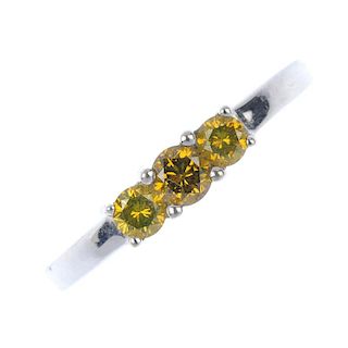An 18ct gold colour treated diamond three-stone ring. The slightly graduated brilliant-cut 'yellow'