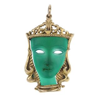 A 1960s 9ct gold dyed chalcedony mask pendant. The carved face, within a scrolling openwork surmount