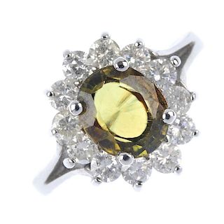 A sphene and diamond cluster ring. The oval-shape sphene, within a brilliant-cut diamond surround, t