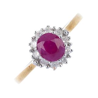A 9ct gold ruby and diamond cluster ring. The oval-shape ruby, within a brilliant-cut diamond surrou