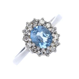 A 9ct gold topaz and diamond cluster ring. The oval-shape blue-topaz, within a brilliant-cut diamond
