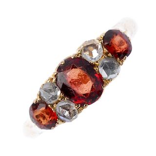 An early 20th century 15ct gold garnet and diamond ring. The graduated oval-shape garnet line, with