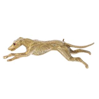 A 9ct gold greyhound brooch. Designed as a running greyhound, with textured body and garnet eye high