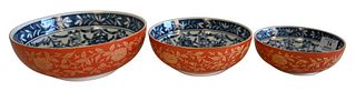 Three Japanese Porcelain Stacking Bowls, having blue and white interior with orange and gold exterior, each on wood stands, largest 2 3/4 inches, diam