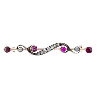 A late 19th century silver and gold, diamond and ruby bar brooch. The scrolling old-cut diamond line