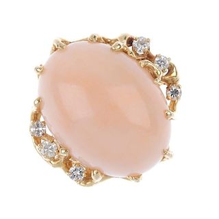 A coral and diamond dress ring. The oval coral cabochon, to the brilliant-cut diamond stylised branc
