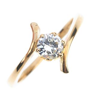 A 14ct gold diamond crossover ring. The brilliant-cut diamond, to the asymmetric shoulders and plain