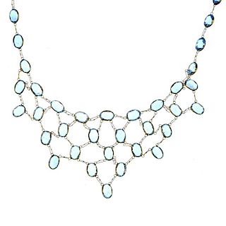 A 9ct gold topaz necklace. The front designed as an oval-shape blue topaz collet lattice, suspended