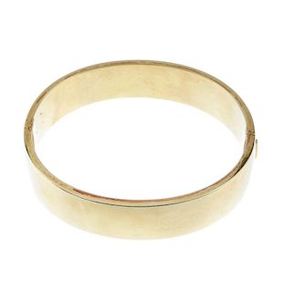 A hinged bangle. The plain polished front, to the similarly designed half-bangle. Inner diameter 6.4