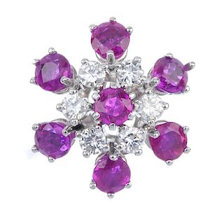 A ruby and diamond floral cluster ring. The circular-shape ruby, within a brilliant-cut diamond and