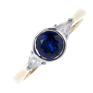 An 18ct gold sapphire and diamond three-stone ring. The circular-shape sapphire collet, with triangu